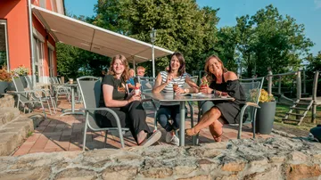 Three women sitting outside enjoying drinks.