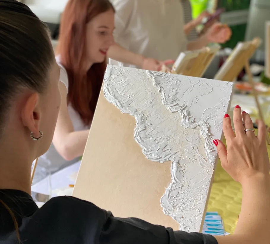 Woman creating textured artwork with paint indoors.