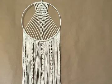 Macramé wall hanging on a brown wall.