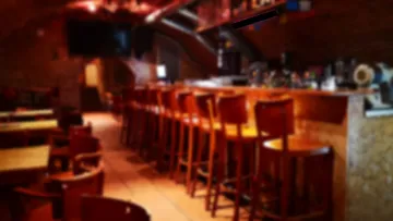 Wooden bar stools in dimly lit pub.