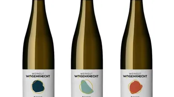 Drei Weinflaschen mit bunten Etiketten.