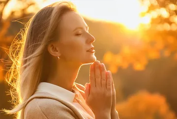 Frau betet im Freien bei Sonnenuntergang.