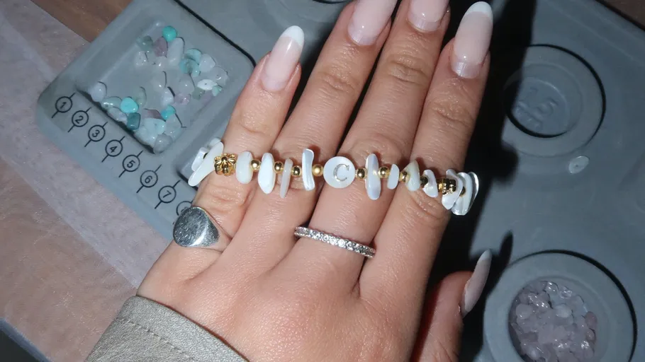 Hand mit Schmuck, Steine im Hintergrund.