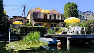 Haus mit Terrasse, gelbe Regenschirme, Seerosen.