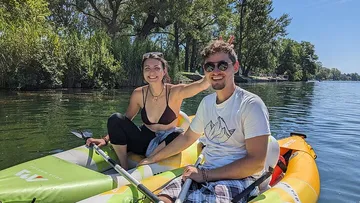 Zwei Personen lächeln in Schlauchboot auf See.