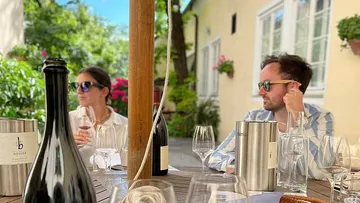 Leute trinken Wein an einem Außentisch.