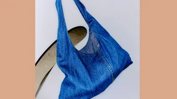 Blaue Denim-Tasche auf weißem Stuhl.