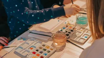People painting with watercolors on table.