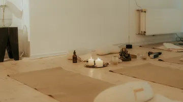 Yoga mats with candles on wooden floor.