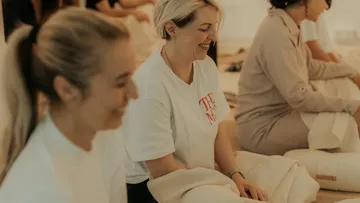 Group of seated women smiling indoors.