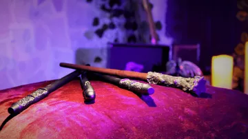Magical wands lying on red cushion, dimly lit room.