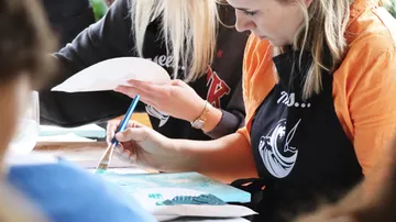Woman painting with brush at table.