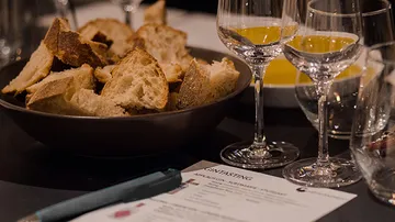 Brot, Weingläser, Papier auf Tisch.