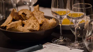 Bread slices in bowl with wine glasses.