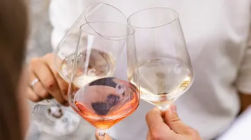 Three people clinking wine glasses outdoors.