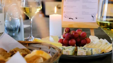 Cheese platter with grapes and wine glasses.