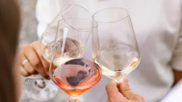 Three people clinking wine glasses together.