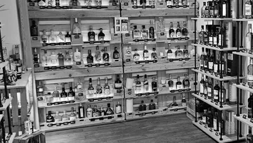 Flaschen auf Holzregalen im Laden ausgestellt.