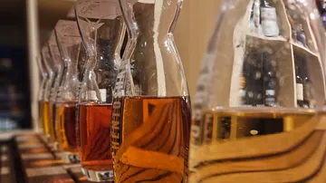Row of whiskey bottles on wooden shelf.