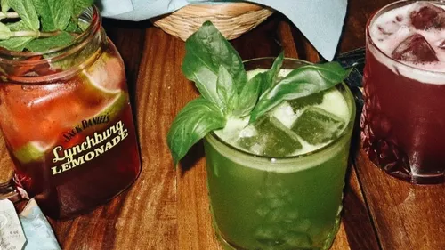 Drei bunte Cocktails auf einem Holztisch.