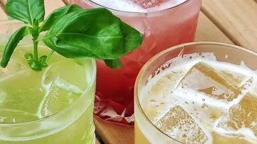 Drei bunte Cocktails auf Holztisch.