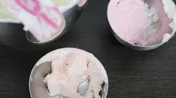 Drei Schüsseln mit rosa Zuckerguss auf Tisch.