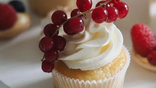 Cupcake with cream and red currants topping.