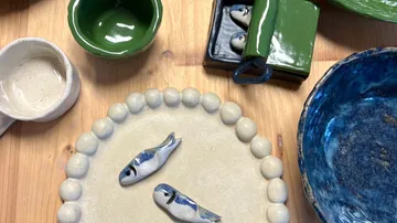Ceramic fish on decorative plates, wooden table.