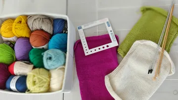 Garnknäuel, Strickproben und Stricknadeln.