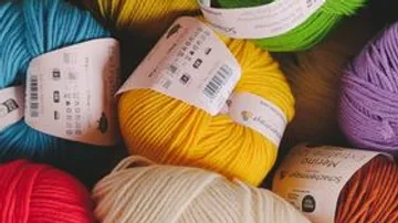 Colorful yarn balls with labels in a pile.