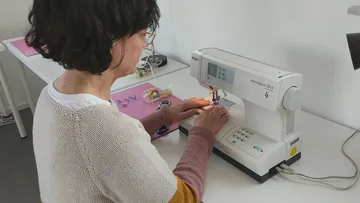 Person näht mit Maschine in einem Raum.