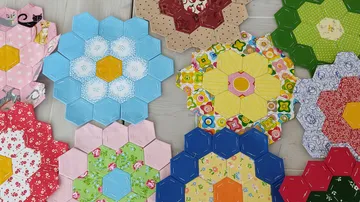 Bunte sechseckige Quiltblöcke auf Boden angeordnet.