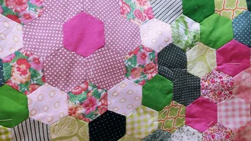 Bunter Quilt mit sechseckigen Stoffflicken.