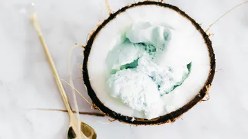 Kokosnuss mit Eiscreme auf Tisch.