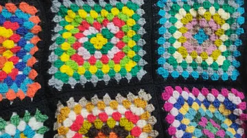 Bunte gehäkelte Quadrate auf schwarzem Hintergrund.