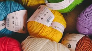 Colorful yarn balls with labels in a pile.