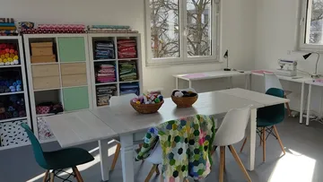 Craft room with tables, chairs, fabric shelves.