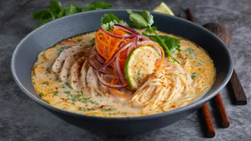 Noodle soup with vegetables in black bowl.