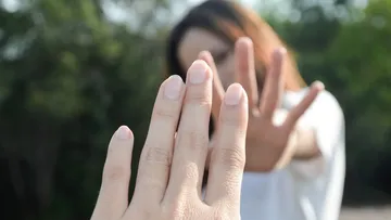 Hands reaching towards each other outdoors.