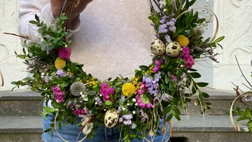 Person holding floral wreath outdoors.