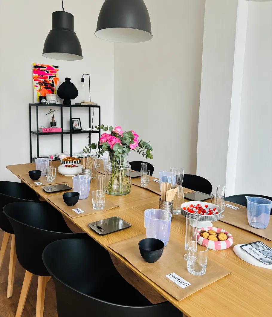 Wooden table setup with pink flowers, kitchen items.