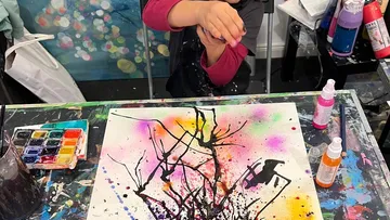 Child painting abstract art at colorful table.
