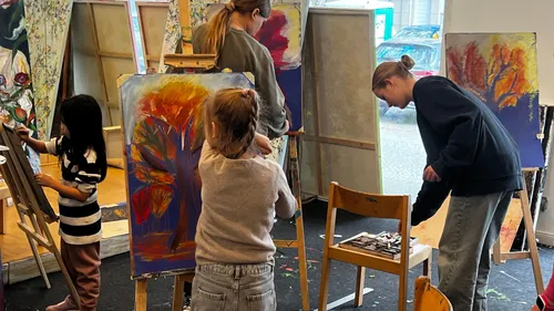 Personen malen bunte Kunstwerke im Atelier.