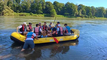 People rafting on a river in a forest.