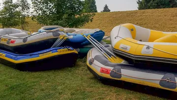 Inflatable boats stacked on grassy area.