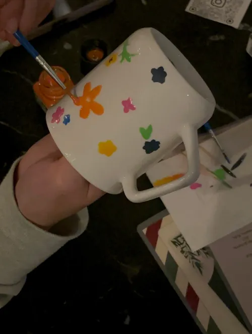 Hand painting colorful flowers on white mug.
