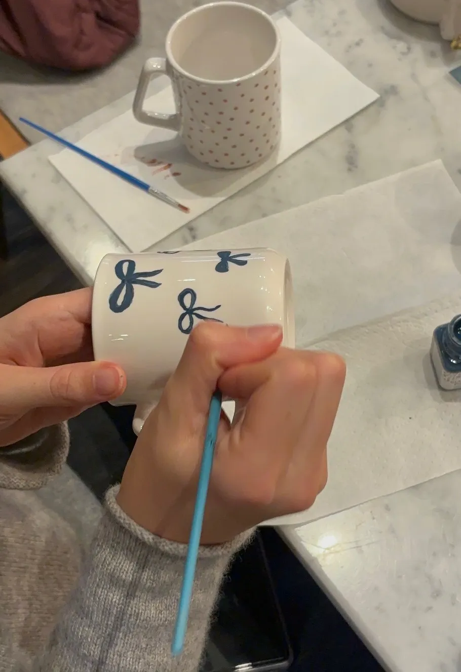 Person malt blaue Muster auf eine Tasse.
