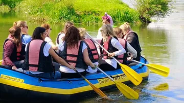 Group rafting on calm river, green surroundings.