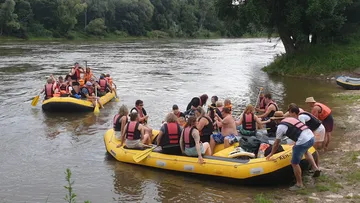 Gruppen besteigen Boote am ruhigen Flussufer.