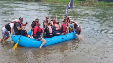 Gruppe im Schlauchboot schiebt in Fluss.